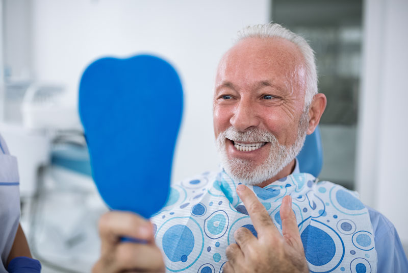 dental patient smiling after full arch dental implants procedure